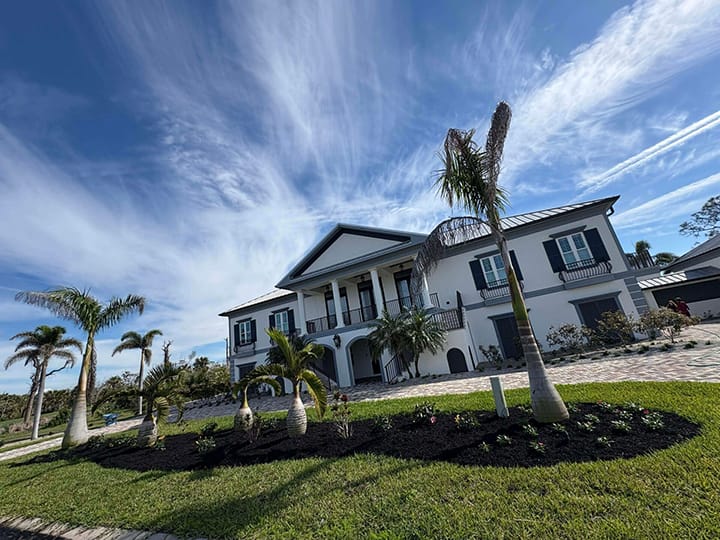 Full landscape bed cleanup with weeding, fresh mulch installation and trimmed bushes, hedges, and palm trees.